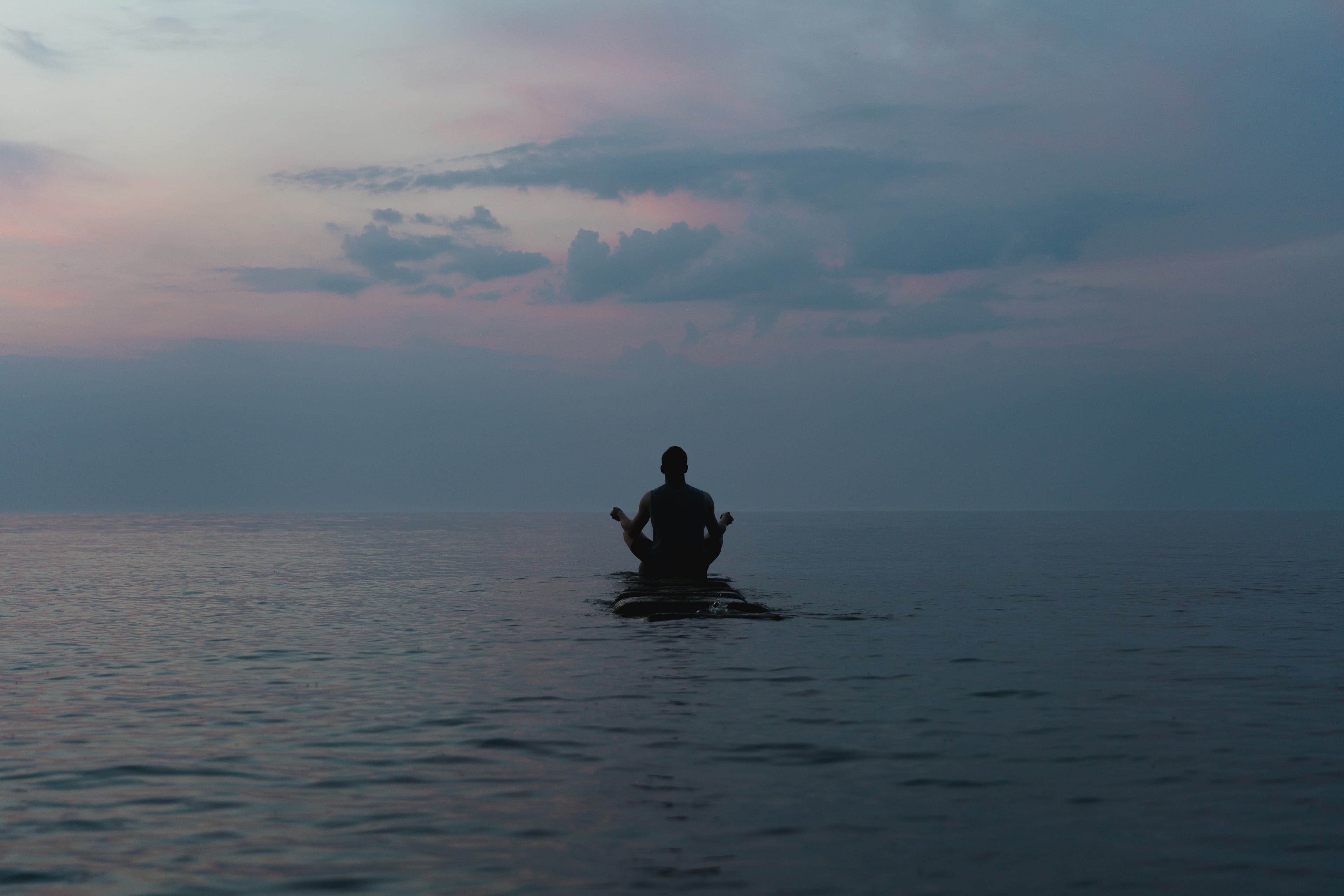 Serene person meditating beside calm water